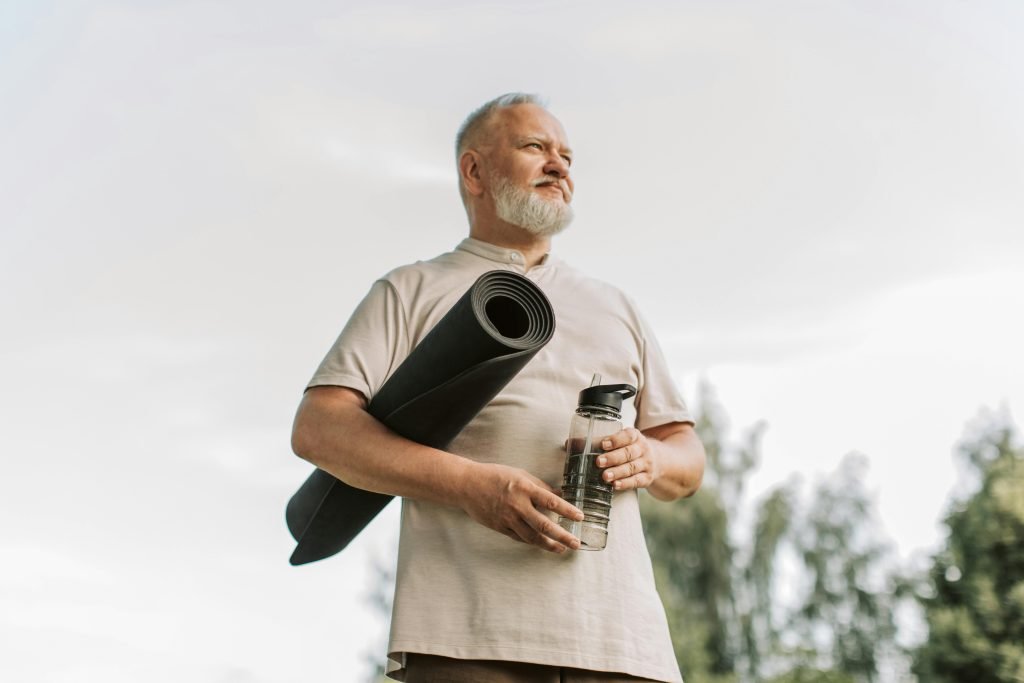 senior man with yoga mat and water bottle